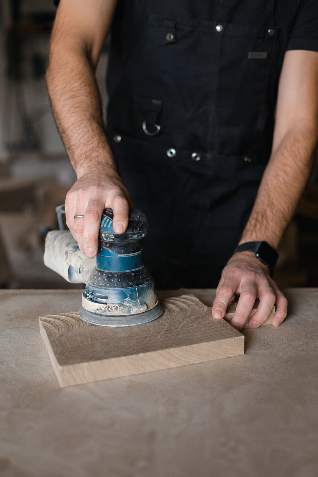 Craftsman sanding the solid wood base of a handmade guitar stand