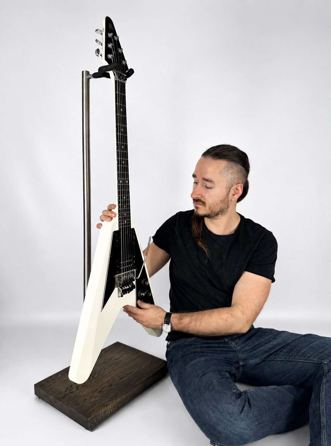 Handmade solid oak stand securely holding a white electric guitar