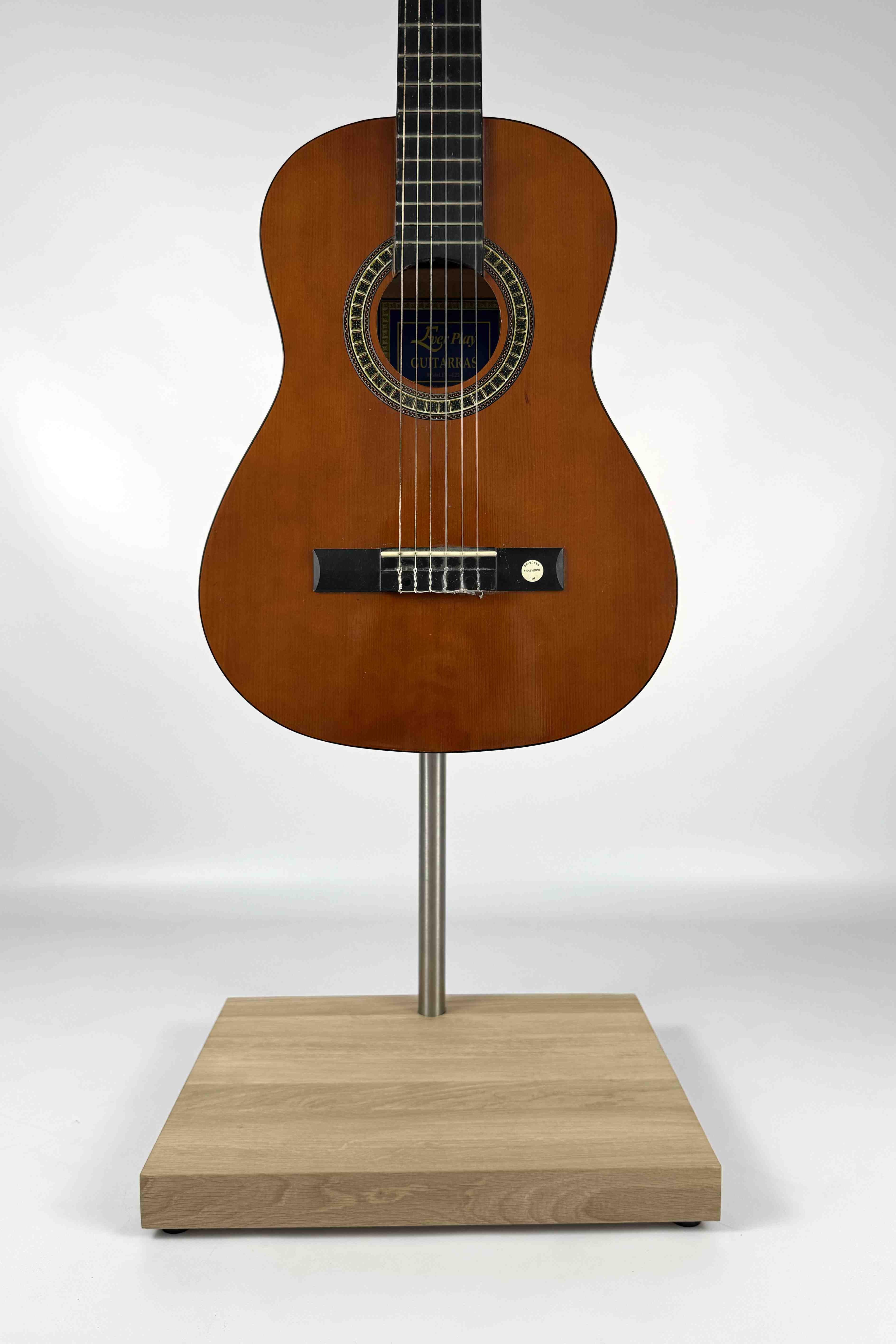 Stable premium handcrafted wooden acoustic guitar stand, with a natural wood finish, holding an acoustic guitar, close-up front view