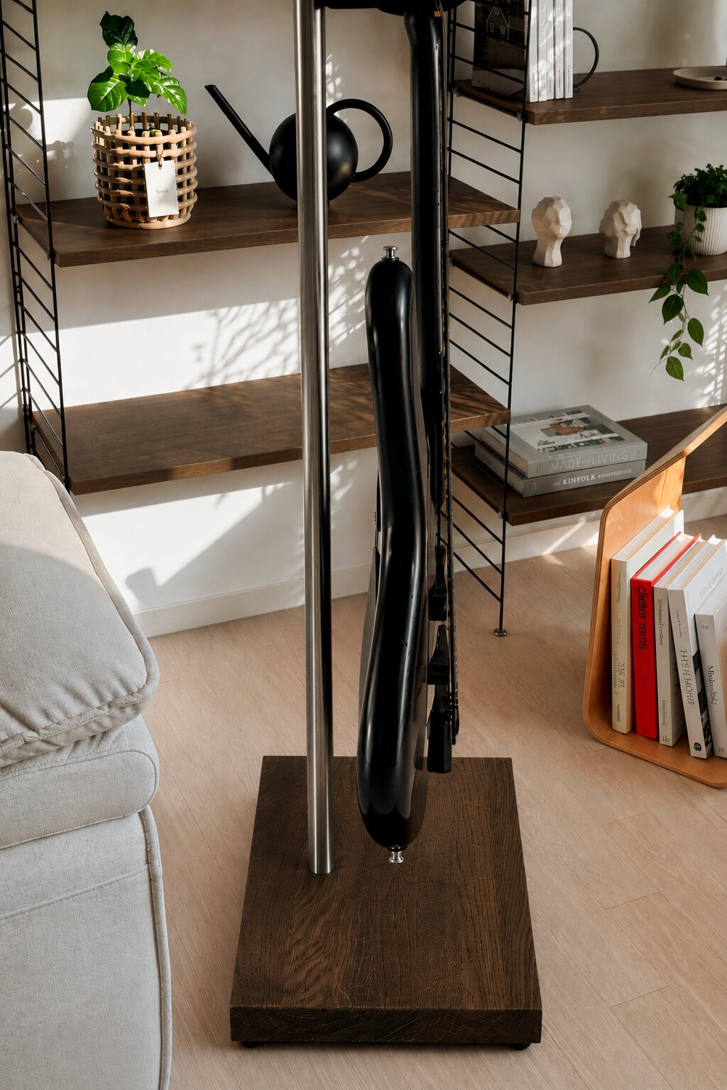 Black electric guitar on a premium handmade stand with a solid wood base in a modern living room.